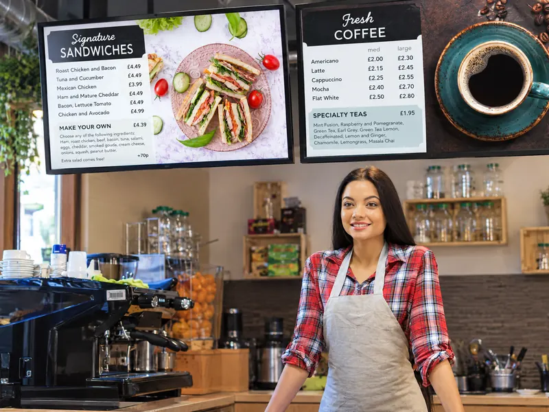 Menu screens above a café counter