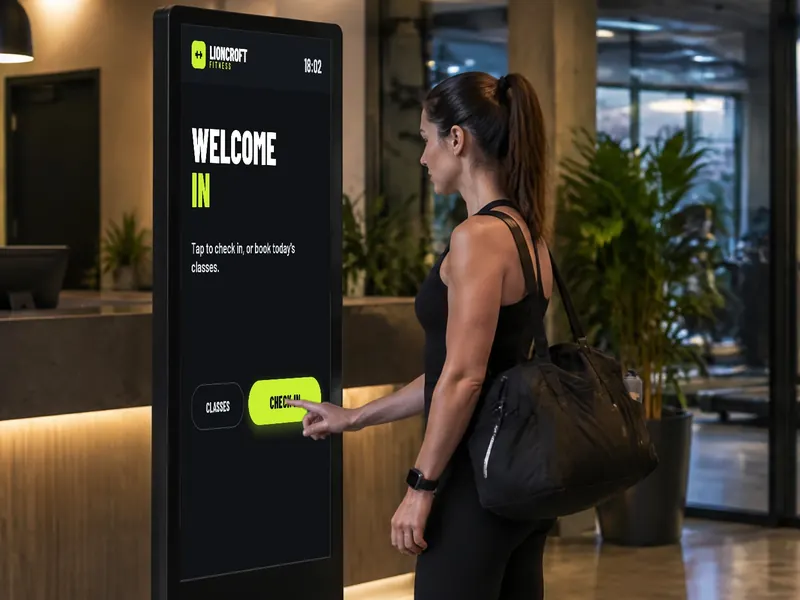 Gym member tapping a touch-screen totem at reception to check in